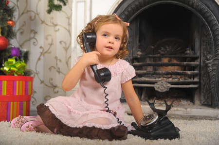 Little girl in  dress talking vintage phone.の写真素材