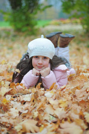 Girl lying amongst autumn leavesの写真素材