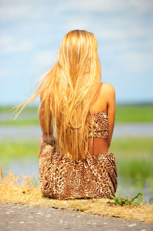 girl sitting on the shore of the lakeの写真素材