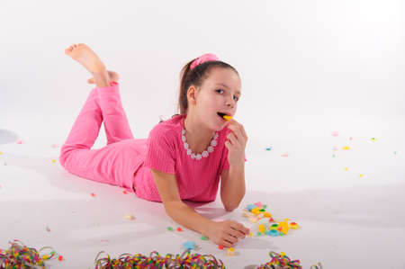 Girl lying among the sweets and chocolatesの写真素材