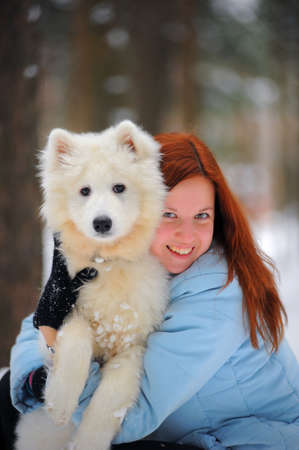 Young red-haired woman in the winter with his puppy Samoyedの写真素材