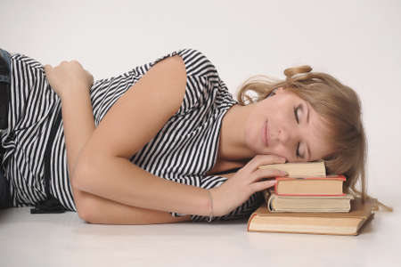 student sleeping on a pile of booksの写真素材