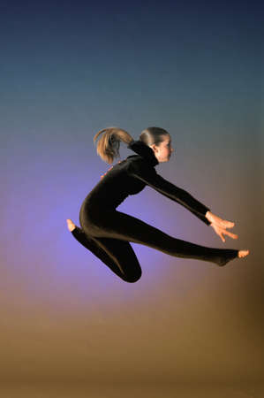 Gymnast jumping in the studio in a black suitの写真素材