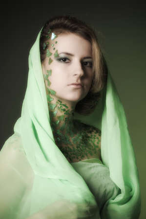 the girl in a green hood with spangles on a neck in the form of an ornamentの写真素材