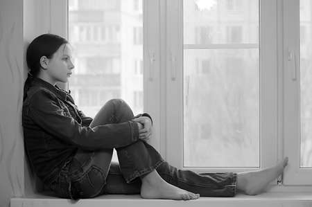 The sad girl the teenager at home on a window sill
