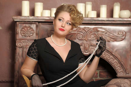 retro photo woman with a black dress with pearl necklace in handの写真素材