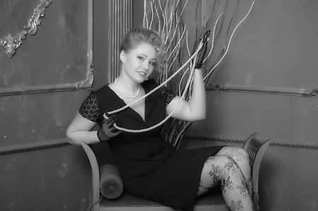 retro photo woman with a black dress with pearl necklace in hand