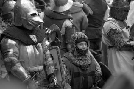 Fight between the pedestrian knights in a heavy armor in a medieval castle against a stone wall , ...