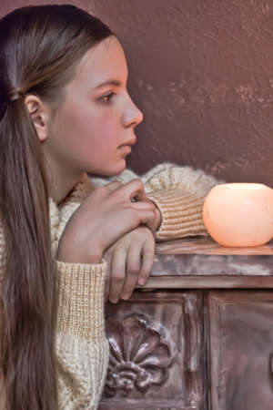 The girl the teenager at a fireplace with candlesの写真素材