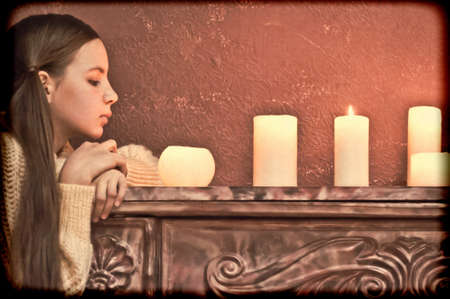 The girl the teenager at a fireplace with candlesの写真素材