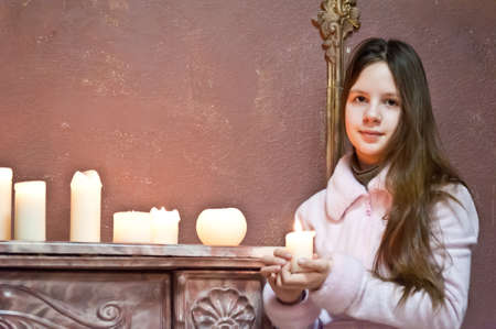 The girl the teenager at a fireplace with candlesの写真素材