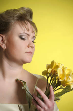 the woman in a yellow dress with flowers in handsの写真素材
