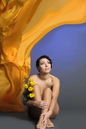 beautiful young woman sitting with yellow rosesの写真素材