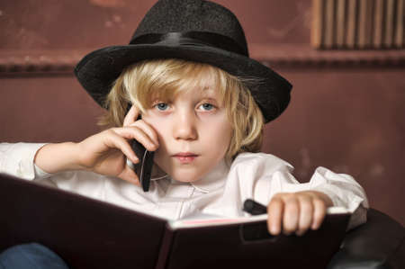 boy in a hat with a mobile phone and a bookの写真素材