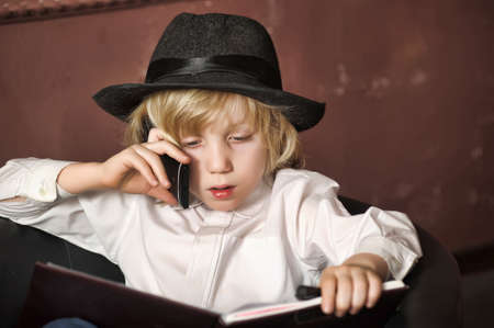 boy in a hat with a mobile phone and a bookの写真素材