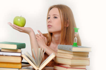 girl student with books, apple and sand-glassesの写真素材
