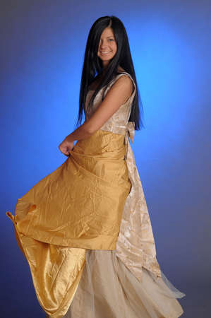 Elegant girl beauty posing in a golden dressの写真素材