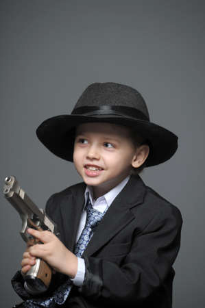 Boy in a suit and a hat with a gun