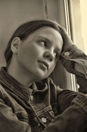 The sad girl the teenager at home on a window sillの写真素材