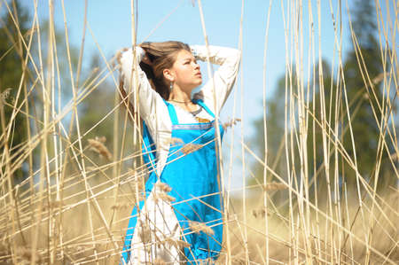 girl in a blue sundress in a field of tall dry grassの写真素材