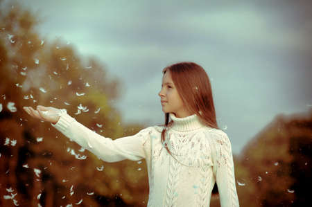 Young beautiful girl filled up by small feathers 