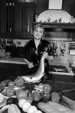 The woman fish at itself on kitchenの写真素材