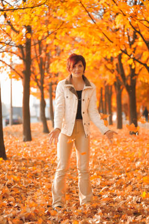 Girl throwing yellow maple leaves in autumnの写真素材