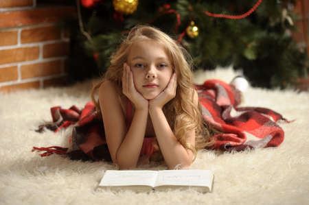 girl reading a book by the fireplace wrapped in a blanketの写真素材
