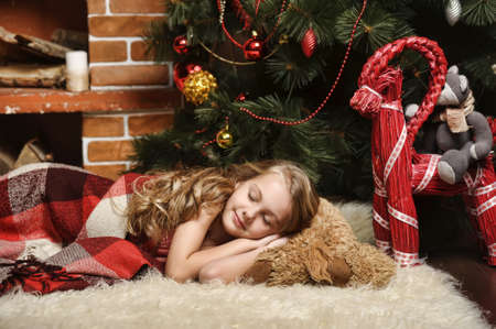 girl sleeping next Christmas treeの写真素材