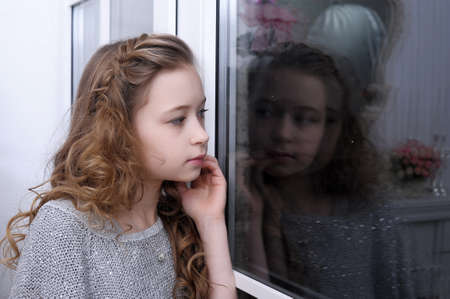teen girl looking out the windowの写真素材