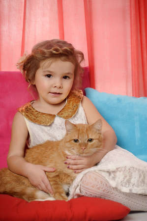 little girl hugging a big red catの写真素材