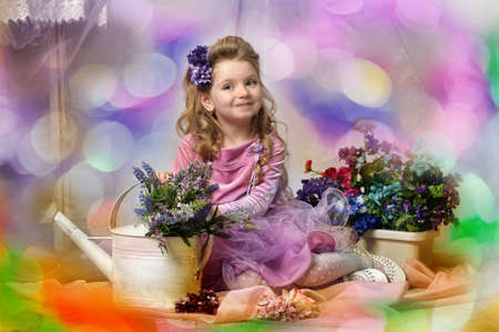 charming little girl with a watering can and flowersの写真素材
