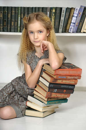 girl holding a pile of books in the libraryの写真素材
