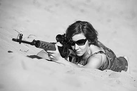 a woman with a gun in the sand