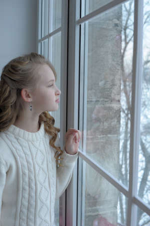 Teen girl at the window in winterの写真素材
