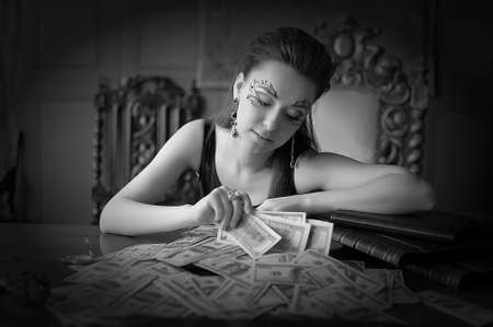 Beautiful girl with creative make-up and a lot of dollars in retro office.の写真素材