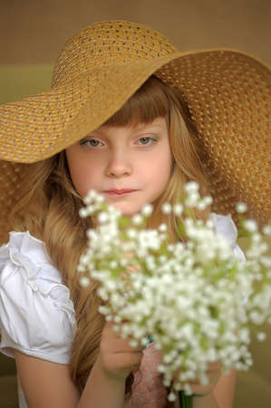 Girl in a straw hat with a bouquet of lilies of the valleyの写真素材