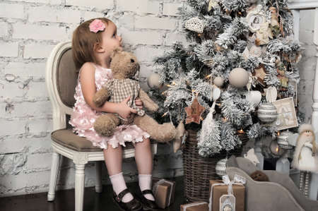 Little girl in a pink dress in retro Christmas interior.の写真素材