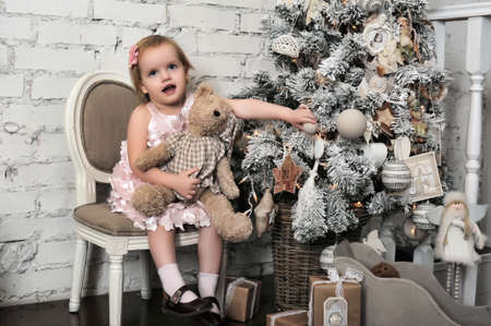 Little girl in a pink dress in retro Christmas interior.の写真素材