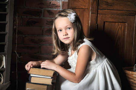 Girl rests on a stack of books, vintage photoの写真素材
