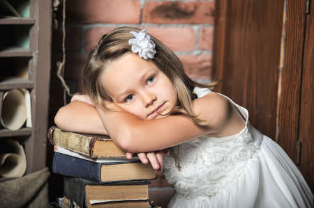 Girl rests on a stack of books, vintage photoの写真素材