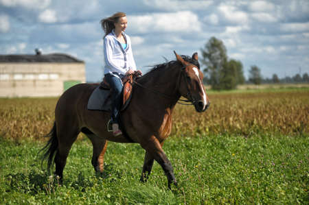 young woman riding a horse in a fieldのeditorial素材