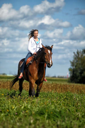 young woman riding a horse in a fieldのeditorial素材