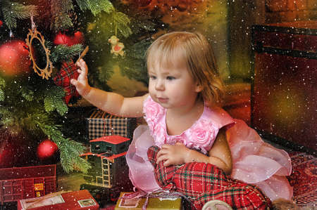 little girl sitting under the Christmas tree with toys