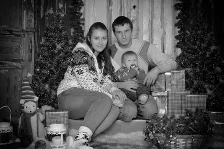 Mom and Dad with son at Christmas among the gifts at the Christmas tree.