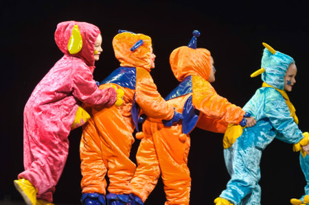 Children in funny colored overalls aliens dancing on stageのeditorial素材