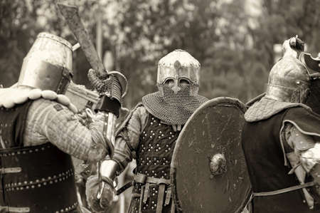 Fight between the pedestrian knights in a heavy armor in a medieval castle against a stone wall, Festival of historical reconstruction, Vyborg, Russia.のeditorial素材