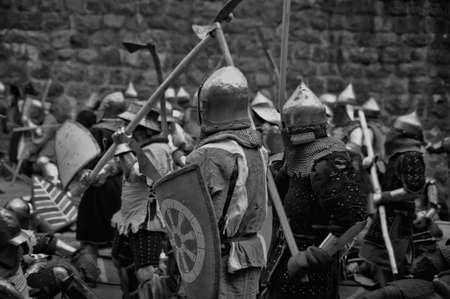 Fight between the pedestrian knights in a heavy armor in a medieval castle against a stone wall, Festival of historical reconstruction, Vyborg, Russia.のeditorial素材