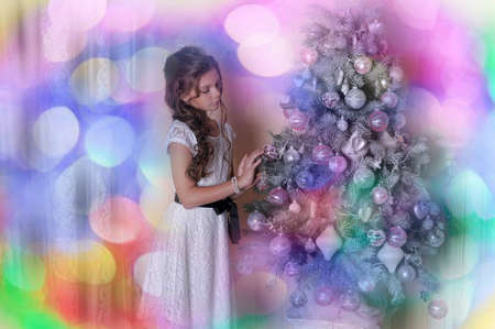 Girl in white dress near Christmas tree.の写真素材