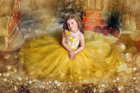 Charming princess girl in a yellow dress in Christmas.